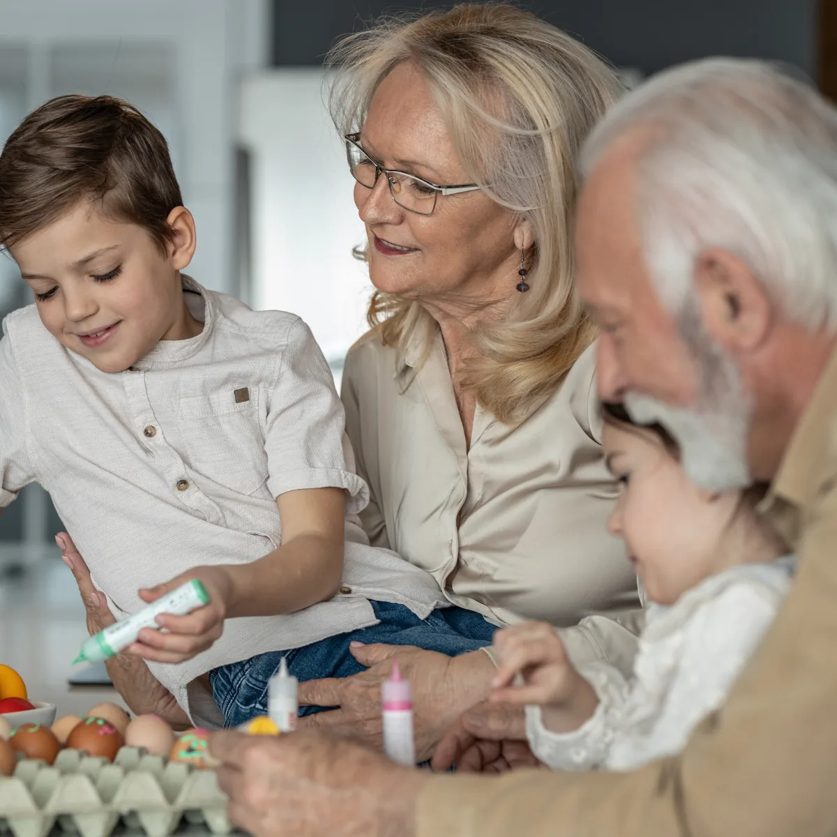 Grandparents and grandchildren decorating eggs together at the kitchen counter